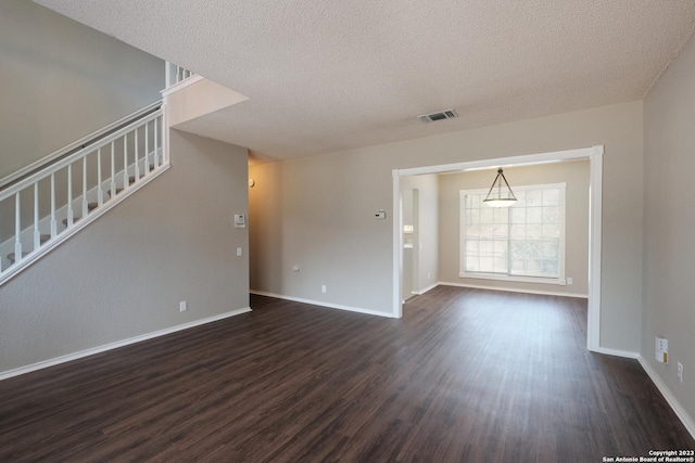unfurnished living room with a textured ceiling, stairway, visible vents, and dark wood-style flooring