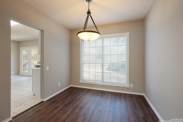 spare room with baseboards, wood finished floors, and a textured ceiling