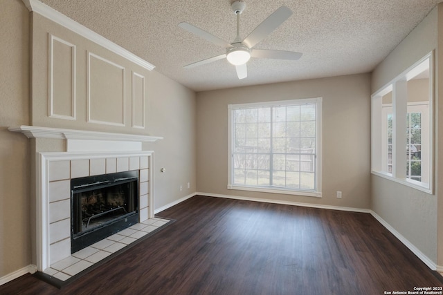 unfurnished living room with a wealth of natural light, a fireplace, dark wood-style floors, and a textured ceiling