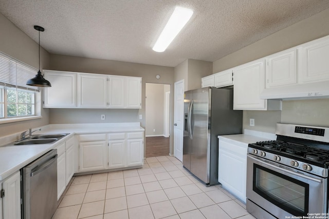 kitchen with a sink, a textured ceiling, light countertops, under cabinet range hood, and appliances with stainless steel finishes