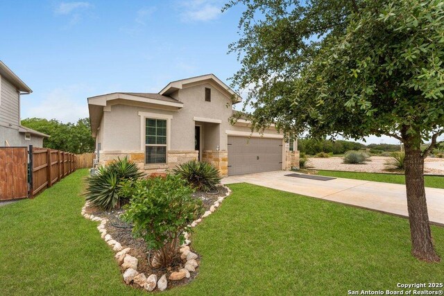 view of front facade with a front lawn, driveway, stone siding, an attached garage, and fence
