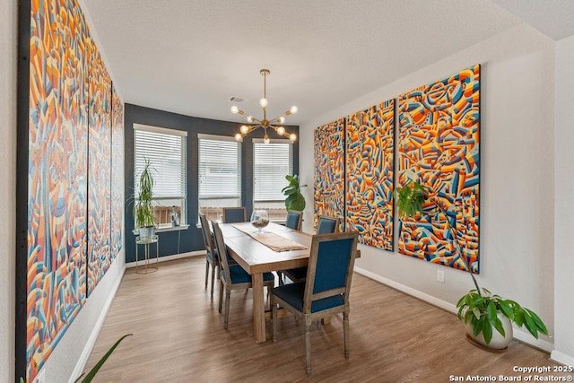 dining space featuring baseboards, wood finished floors, a chandelier, and visible vents