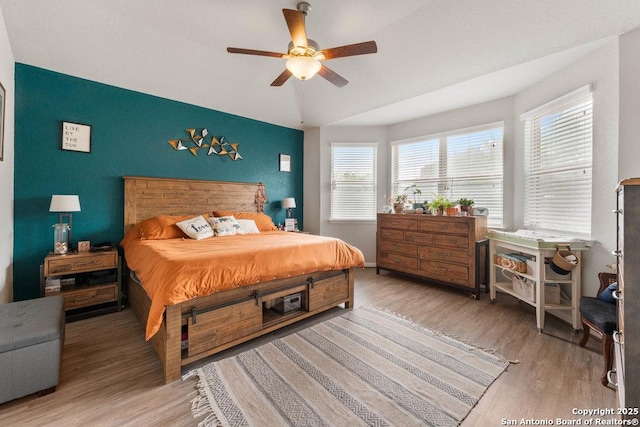 bedroom featuring lofted ceiling, multiple windows, and wood finished floors