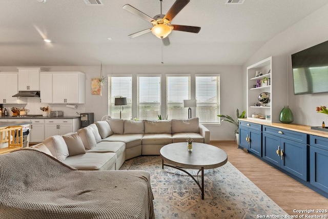 living room with ceiling fan, lofted ceiling, visible vents, and light wood finished floors