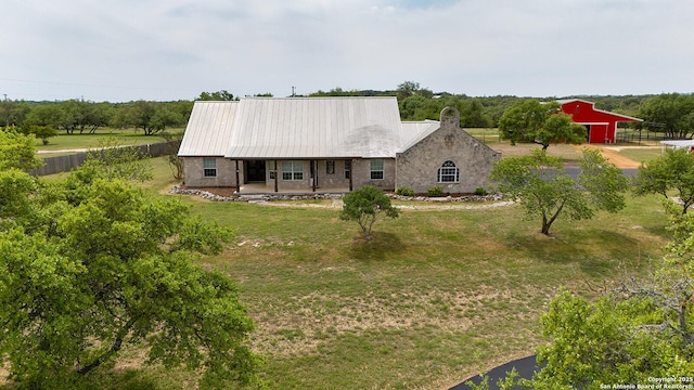 rear view of property featuring a lawn, an outdoor structure, fence, a porch, and metal roof