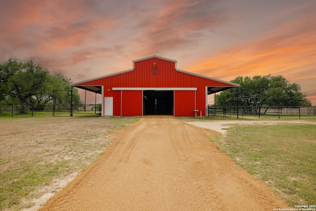 view of pole building featuring fence, a yard, and driveway