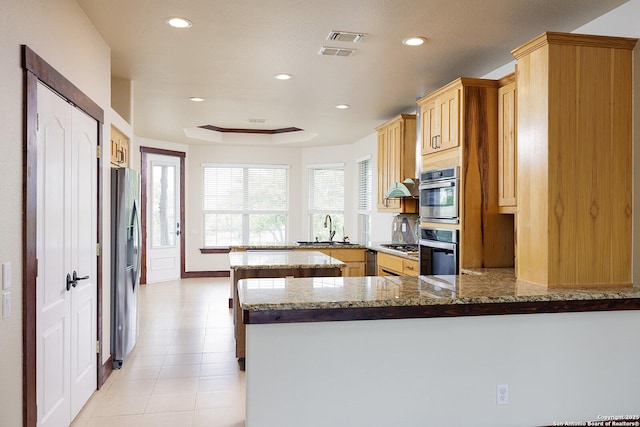 kitchen with a peninsula, appliances with stainless steel finishes, recessed lighting, and a sink