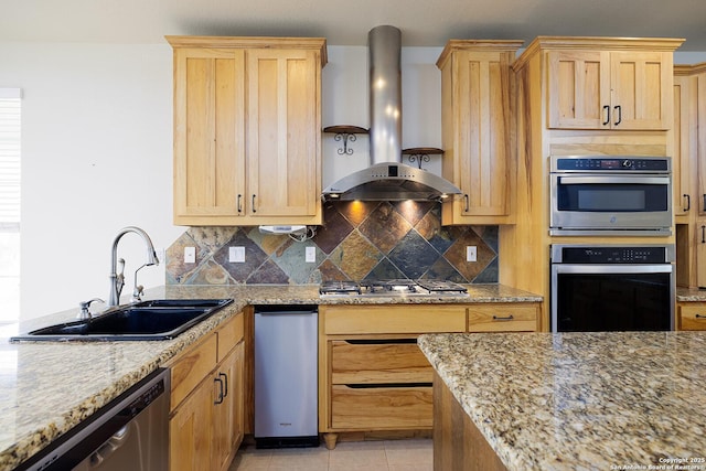 kitchen with wall chimney exhaust hood, tasteful backsplash, stainless steel appliances, and a sink