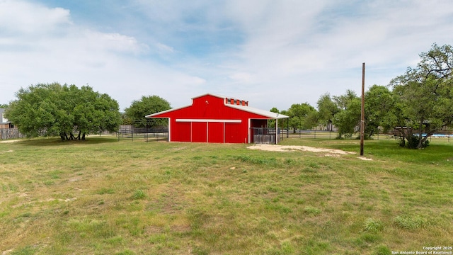 view of yard featuring fence, an outdoor structure, a pole building, and a garage