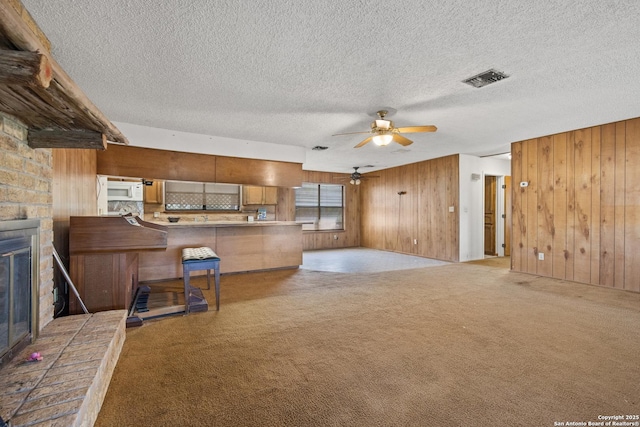 16759 County Road 1726, Odem, TX 78370 - unfurnished living room featuring a fireplace, wooden walls, carpet floors, and ceiling fan