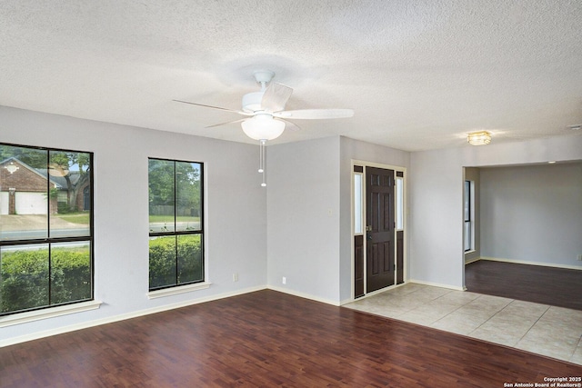 spare room with baseboards, a ceiling fan, wood finished floors, and a textured ceiling