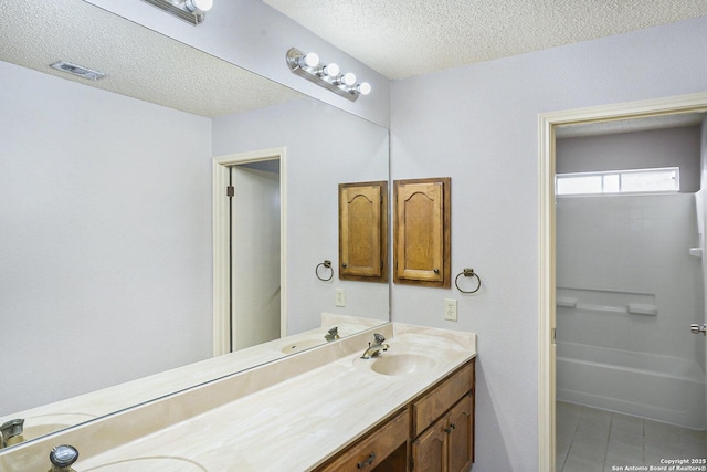 full bath with a sink, a textured ceiling, double vanity, visible vents, and tile patterned flooring