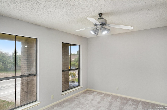 carpeted empty room featuring baseboards, a ceiling fan, and a textured ceiling