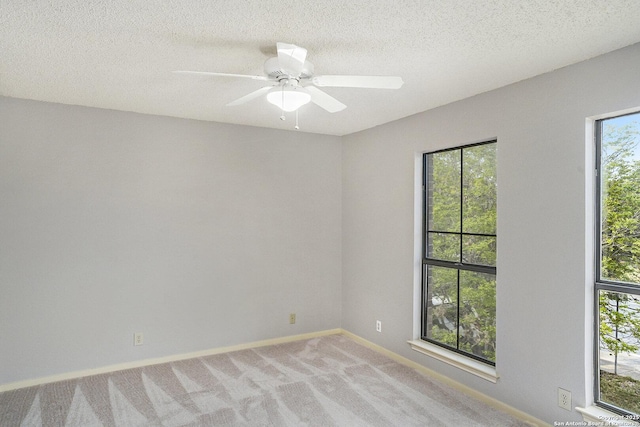spare room with light carpet, a ceiling fan, a textured ceiling, and baseboards