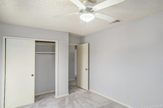 unfurnished bedroom with a textured ceiling, baseboards, visible vents, carpet, and a closet