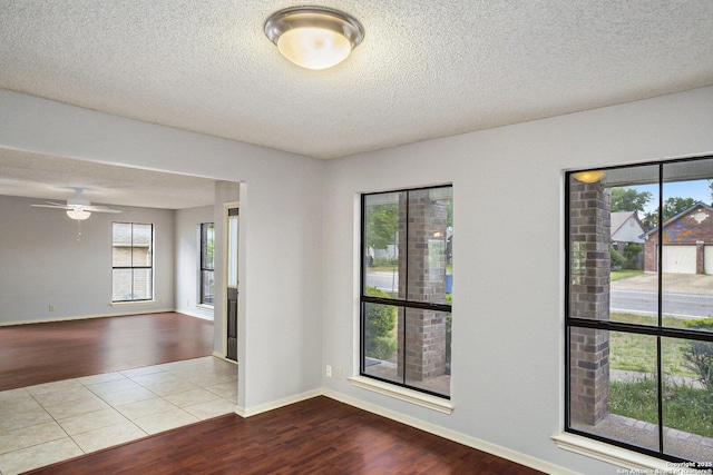 unfurnished room featuring baseboards, wood finished floors, and a textured ceiling