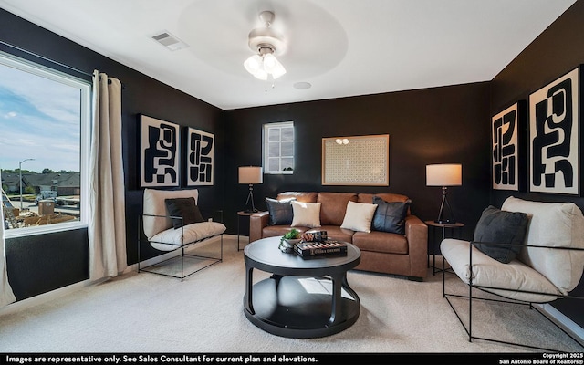 carpeted living room featuring a wealth of natural light, visible vents, and a ceiling fan