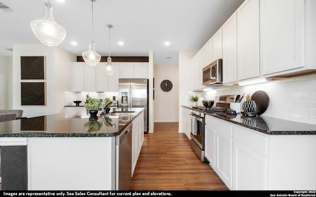 kitchen featuring visible vents, appliances with stainless steel finishes, wood finished floors, a center island with sink, and decorative backsplash