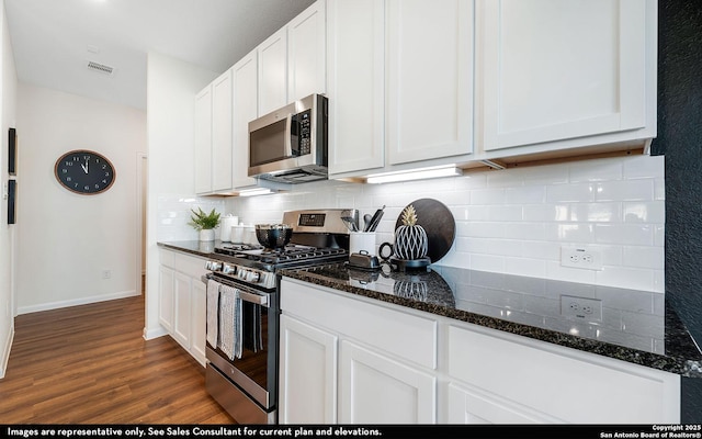 kitchen featuring dark wood-style flooring, white cabinets, visible vents, decorative backsplash, and appliances with stainless steel finishes