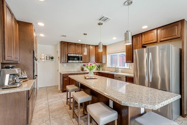 kitchen featuring visible vents, a sink, a kitchen bar, and stainless steel appliances