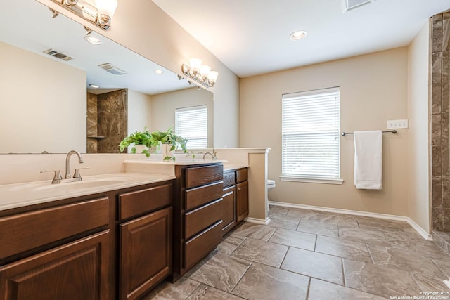 full bath with double vanity, visible vents, a tile shower, a sink, and toilet