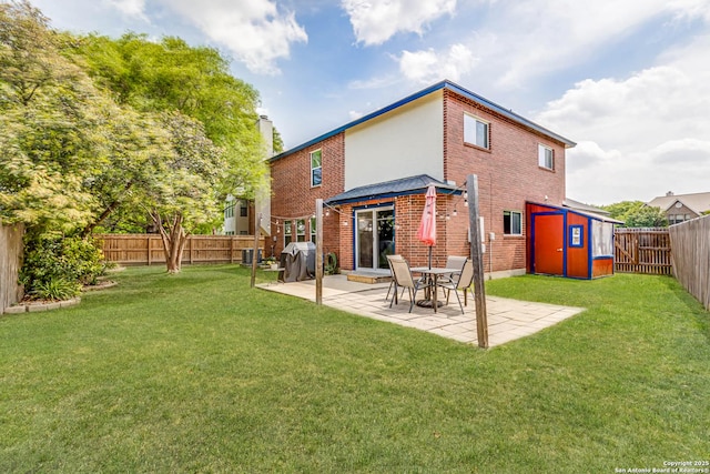 rear view of property with a lawn, an outbuilding, a patio area, a fenced backyard, and a storage unit