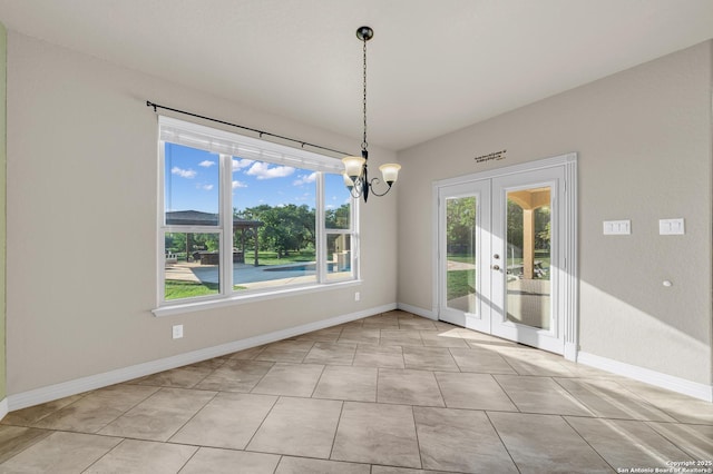 unfurnished dining area featuring baseboards, a notable chandelier, and french doors