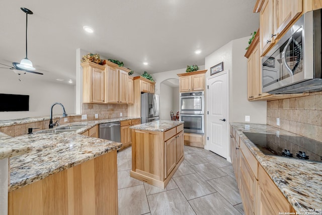 kitchen featuring light brown cabinetry, light stone counters, a sink, tasteful backsplash, and appliances with stainless steel finishes