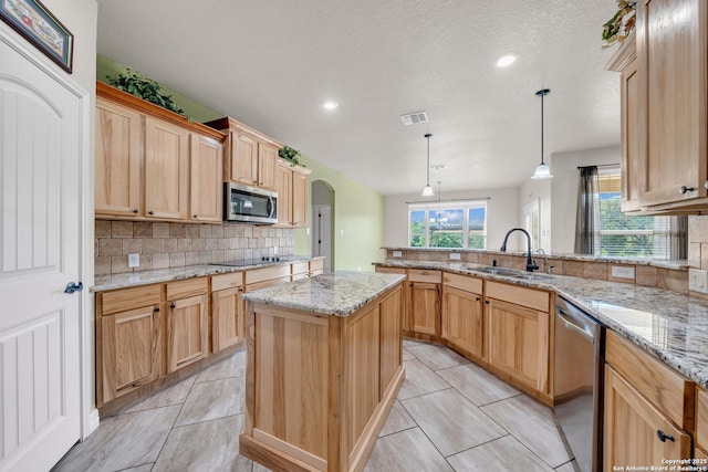 kitchen with stainless steel appliances, a peninsula, a sink, tasteful backsplash, and visible vents