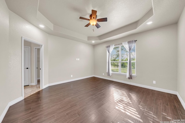 empty room with recessed lighting, a raised ceiling, wood finished floors, baseboards, and ceiling fan