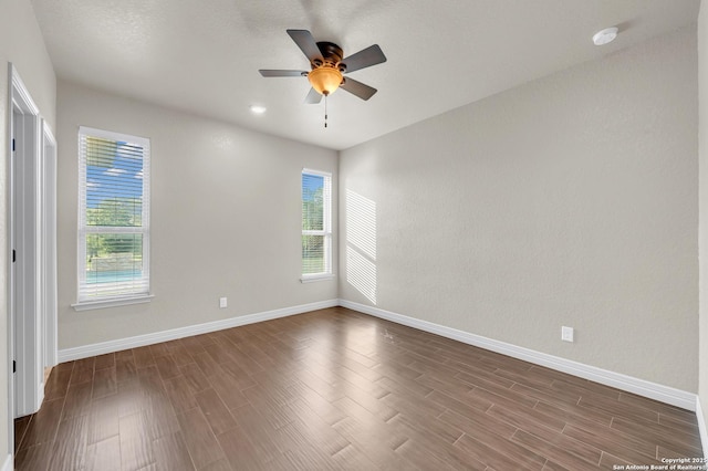 unfurnished room with baseboards, a ceiling fan, dark wood-style floors, and a healthy amount of sunlight
