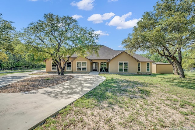 view of front of house featuring stucco siding, a front lawn, driveway, and a shingled roof