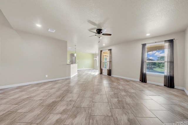 spare room with a textured ceiling, ceiling fan, baseboards, visible vents, and recessed lighting