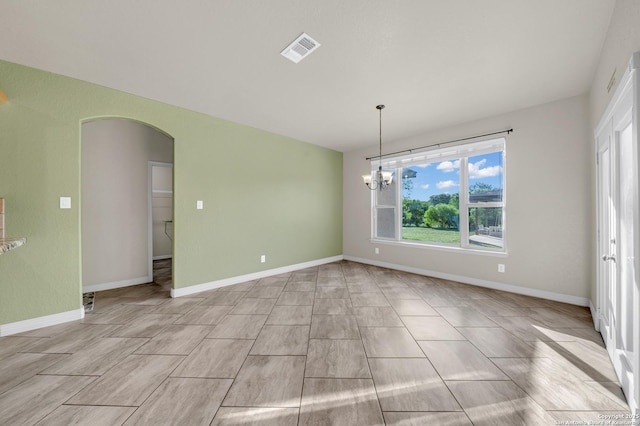 unfurnished dining area with arched walkways, an inviting chandelier, visible vents, and baseboards