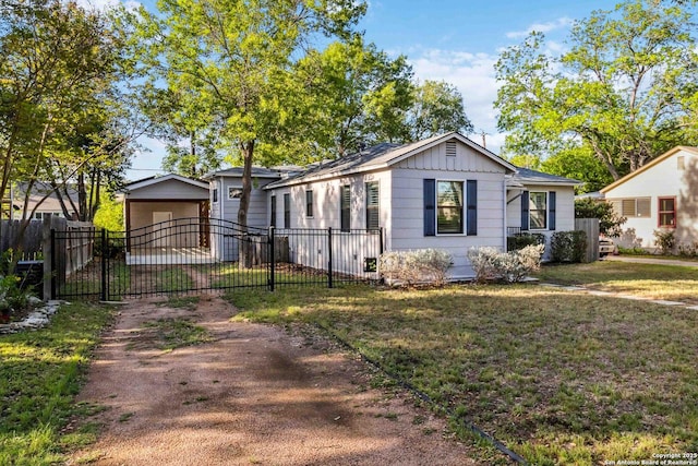 view of front of home featuring a gate, fence, dirt driveway, and a front yard