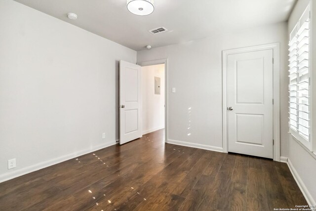 unfurnished bedroom featuring baseboards, visible vents, multiple windows, and dark wood-style floors