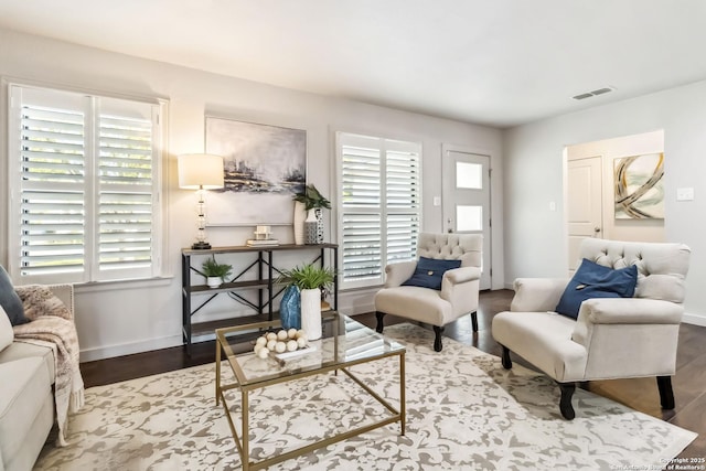 living area with baseboards, wood finished floors, visible vents, and plenty of natural light