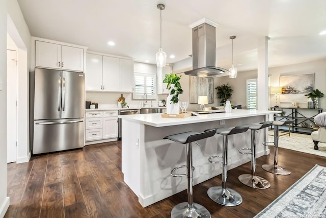 kitchen with island exhaust hood, a kitchen bar, light countertops, dark wood-type flooring, and appliances with stainless steel finishes