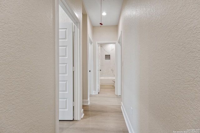 114 S Minter St, San Antonio, TX 78207 - hallway featuring a textured wall, baseboards, and light wood-style floors