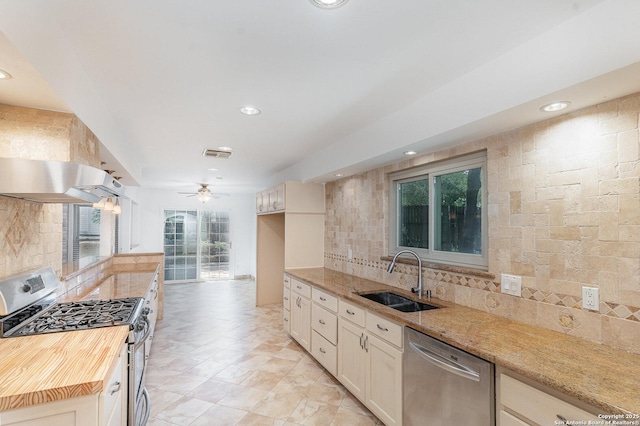 kitchen featuring light stone counters, a sink, decorative backsplash, stainless steel appliances, and recessed lighting