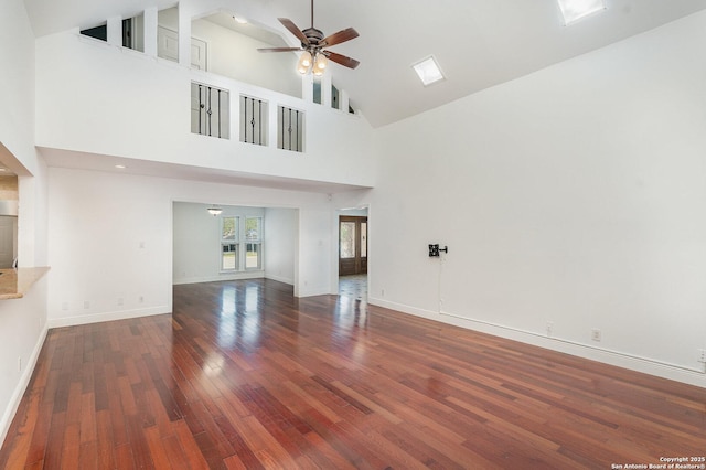 unfurnished living room featuring hardwood / wood-style flooring, baseboards, a ceiling fan, and high vaulted ceiling