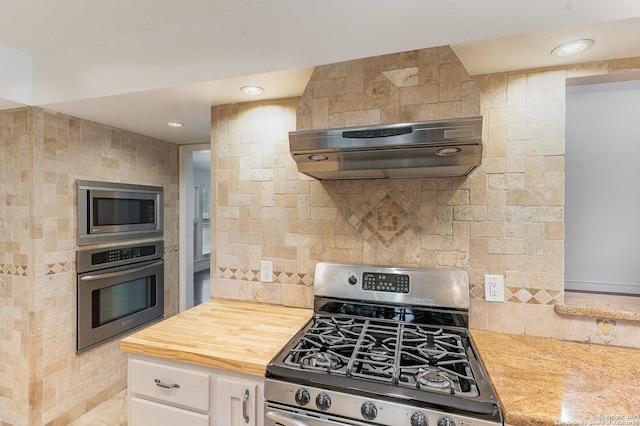 kitchen with extractor fan, decorative backsplash, wood counters, stainless steel appliances, and white cabinetry