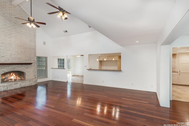 unfurnished living room featuring visible vents, a brick fireplace, ceiling fan, hardwood / wood-style floors, and high vaulted ceiling