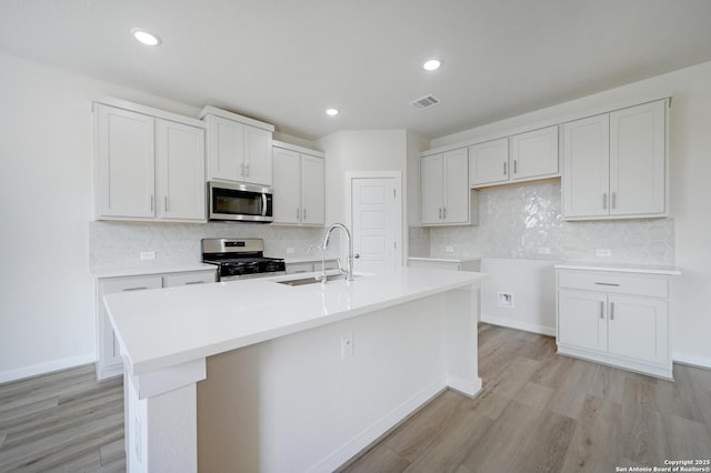 6031 Calgary Park, San Antonio, TX 78233 - kitchen featuring appliances with stainless steel finishes, a sink, a kitchen island with sink, light wood-style flooring, and recessed lighting
