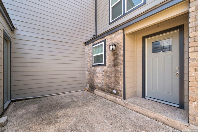 entrance to property with brick siding and a patio