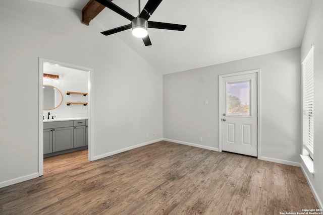 unfurnished bedroom featuring vaulted ceiling with beams, wood finished floors, and multiple windows