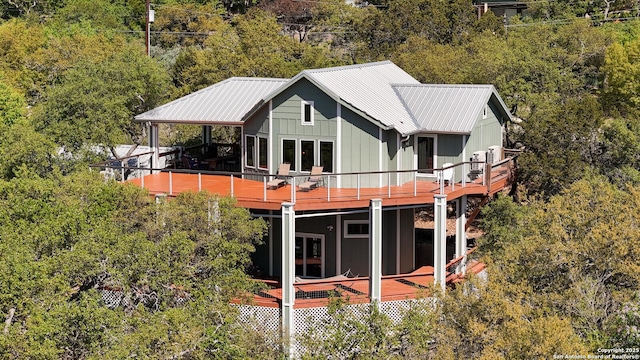 rear view of house with board and batten siding, metal roof, and a deck