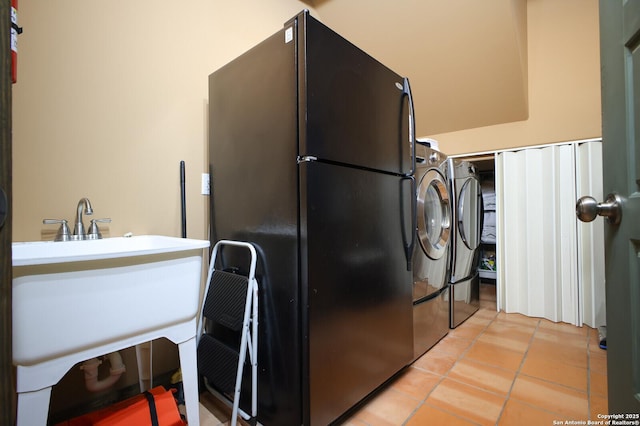 washroom featuring a sink, laundry area, light tile patterned floors, and washer / clothes dryer