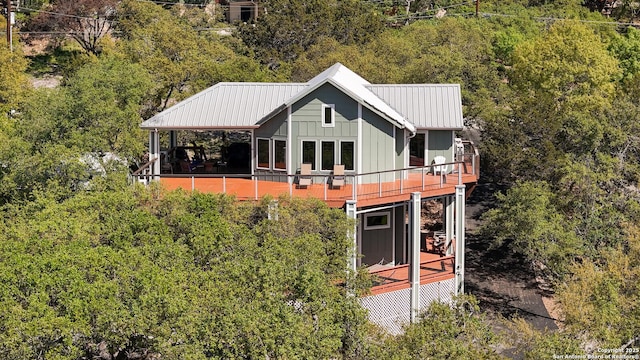 rear view of property featuring board and batten siding, a forest view, and metal roof