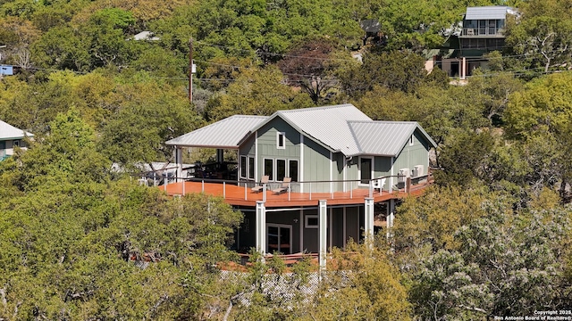 rear view of property with a forest view, a wooden deck, and metal roof
